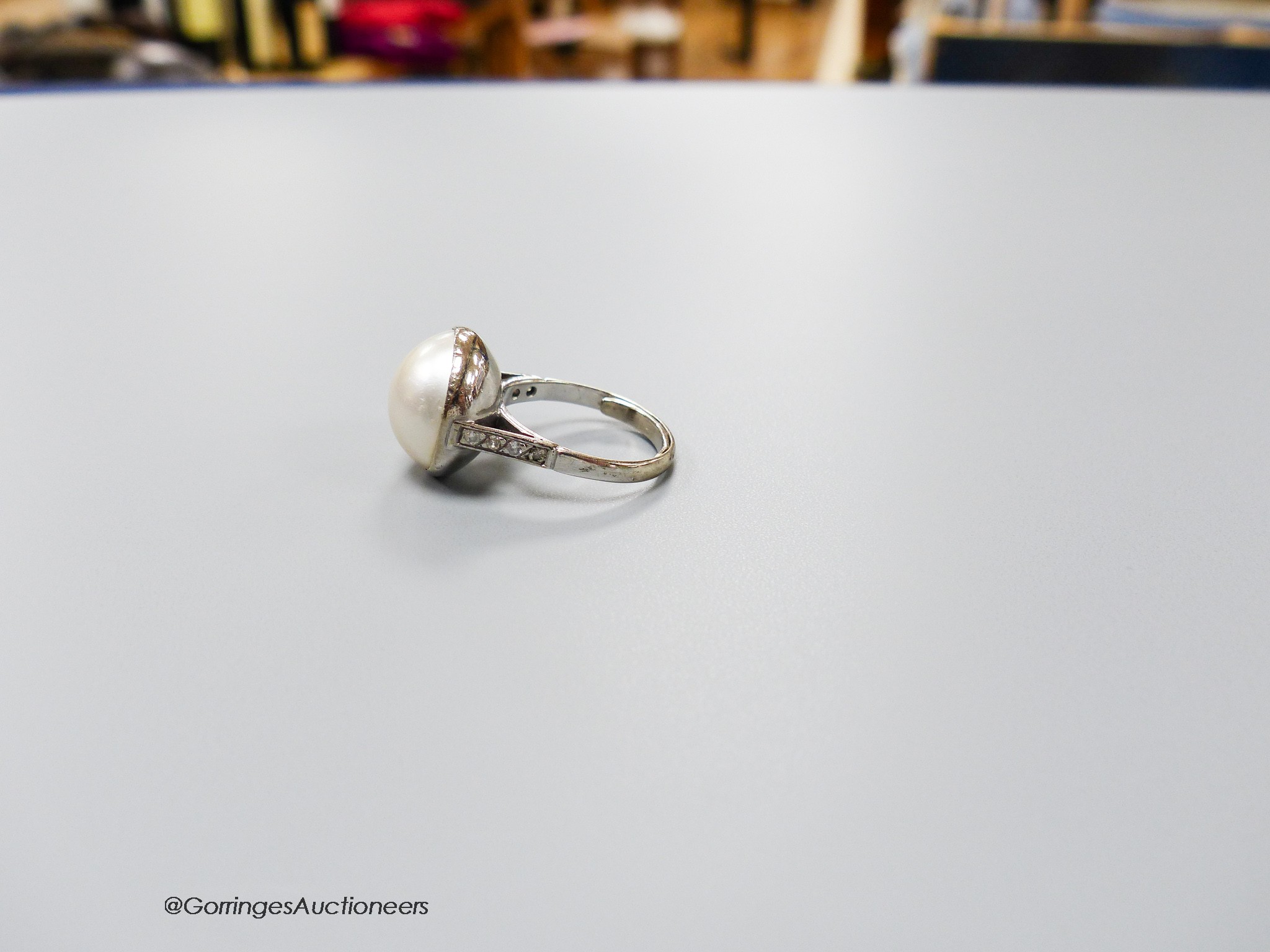 An 18ct white metal and mabe pearl set dress ring with diamond set shoulders, size N, gross 7.2 grams.